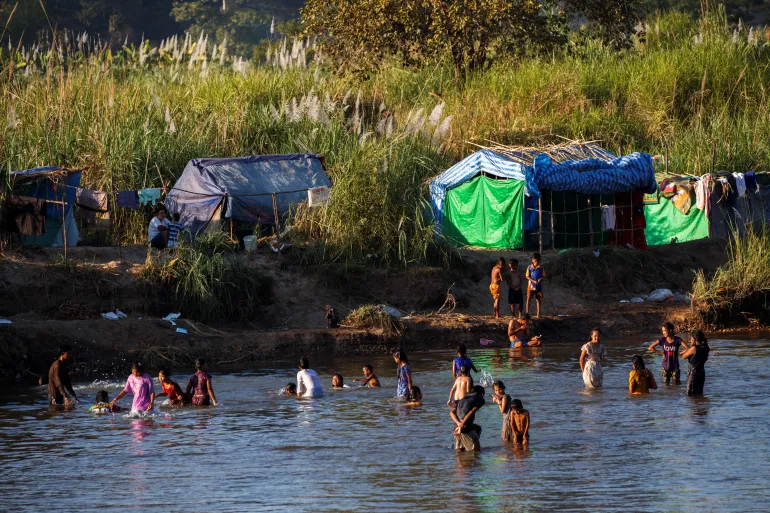 Refugees, who have fled a flare-up in fighting between the Myanmar military and armed groups, bathe in the river waters on the Thai-Myanmar border, in Mae Sot, Thailand, January 7, 2022 [File: Athit Perawongmetha/ Reuters]