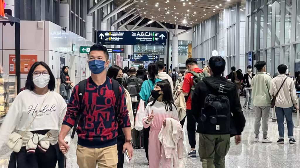 Travelers walk through the Kuala Lumpur International Airport on Dec. 20. As the number of tourists surges across Southeast Asia, so too are COVID cases. (Photo by Norman Goh / asia.nikkei.com)
