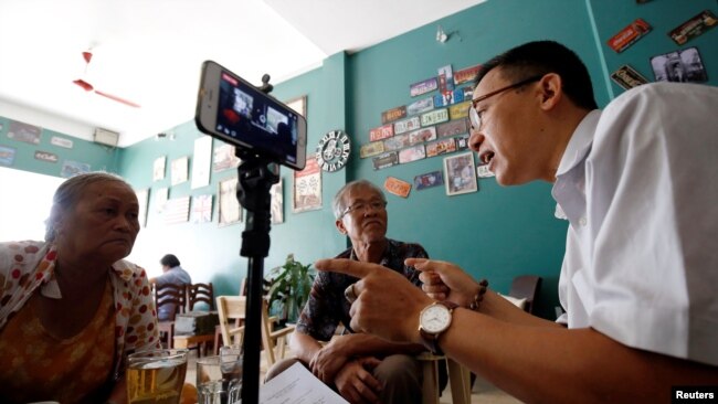 FILE - Journalist and rights activist Le Van Dung (R) conducts a livestream on Facebook in a coffee shop in Hanoi, Vietnam, May 15, 2018.